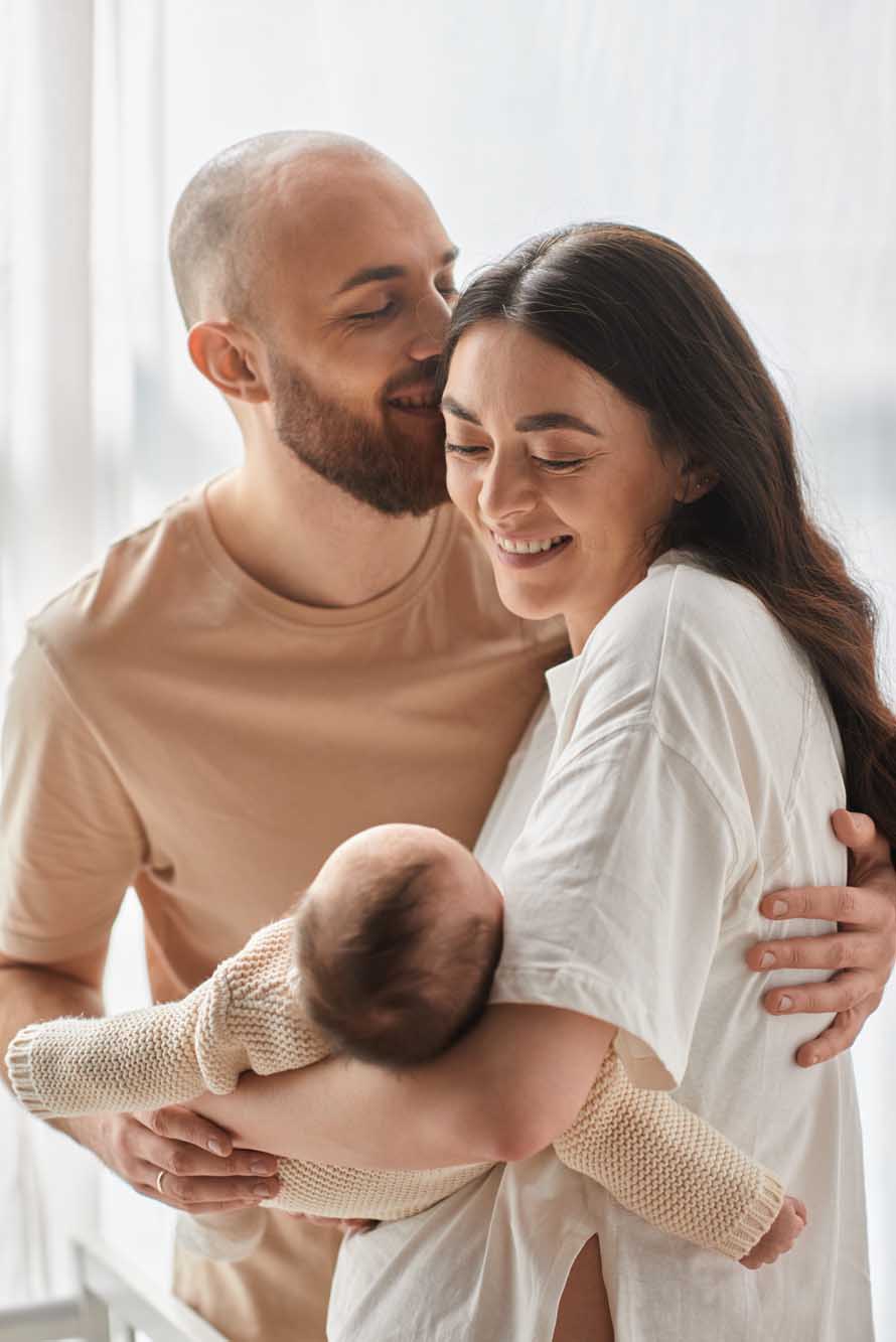 vertical shot of jolly happy parents hugging lovingly and holdin