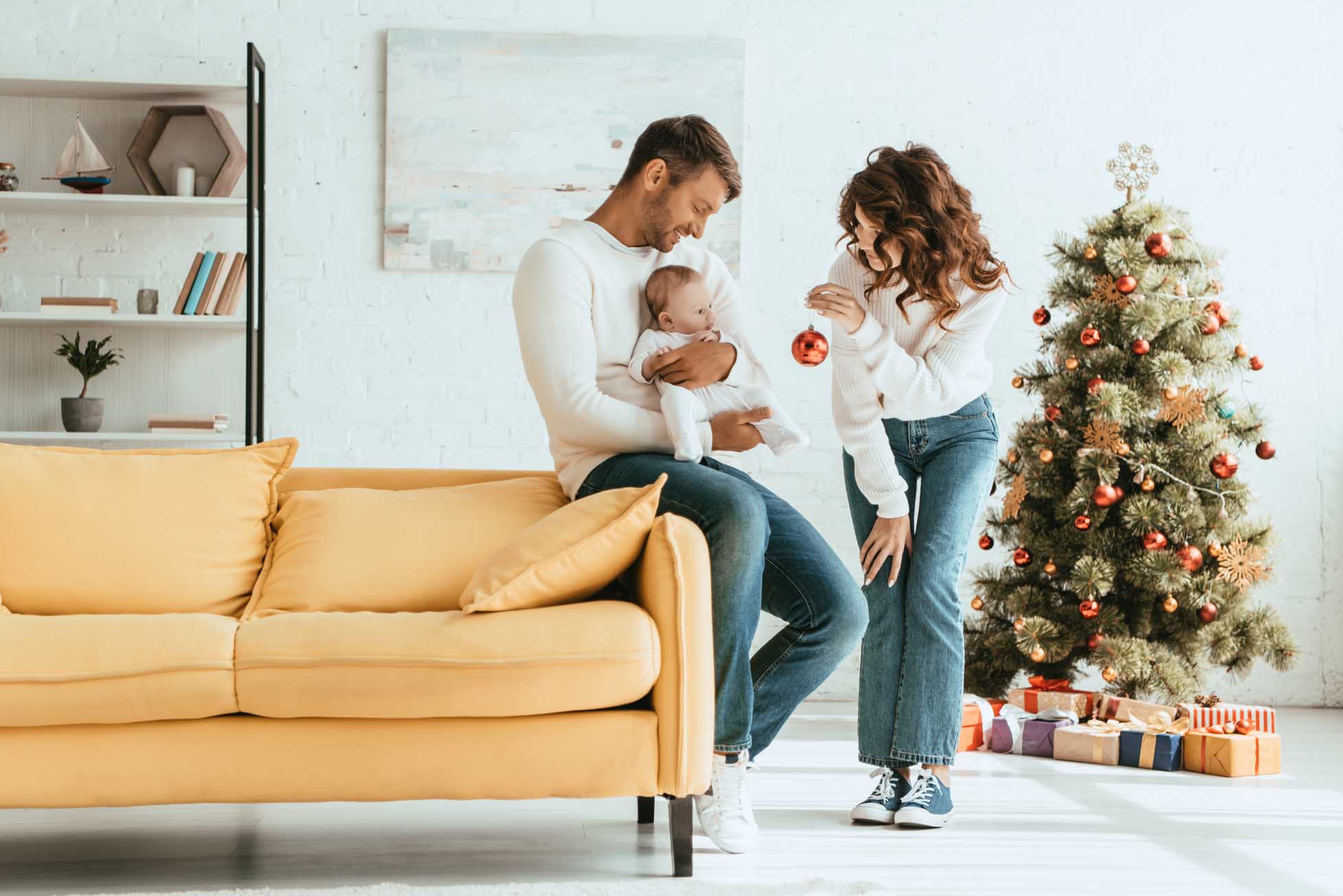 attractive woman showing christmas ball to little child sitting