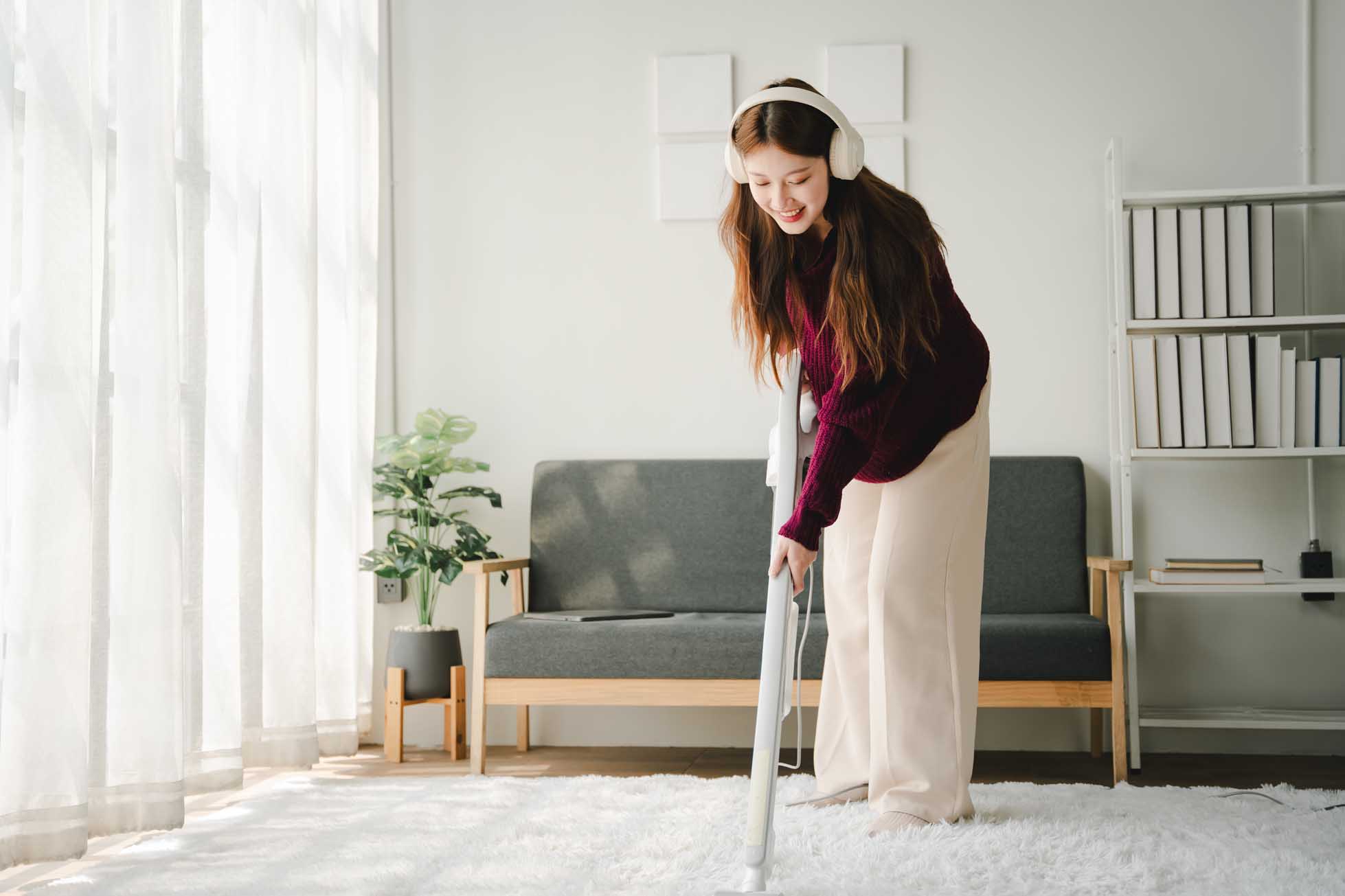 Carefree young woman sings happily while cleaning the house as a