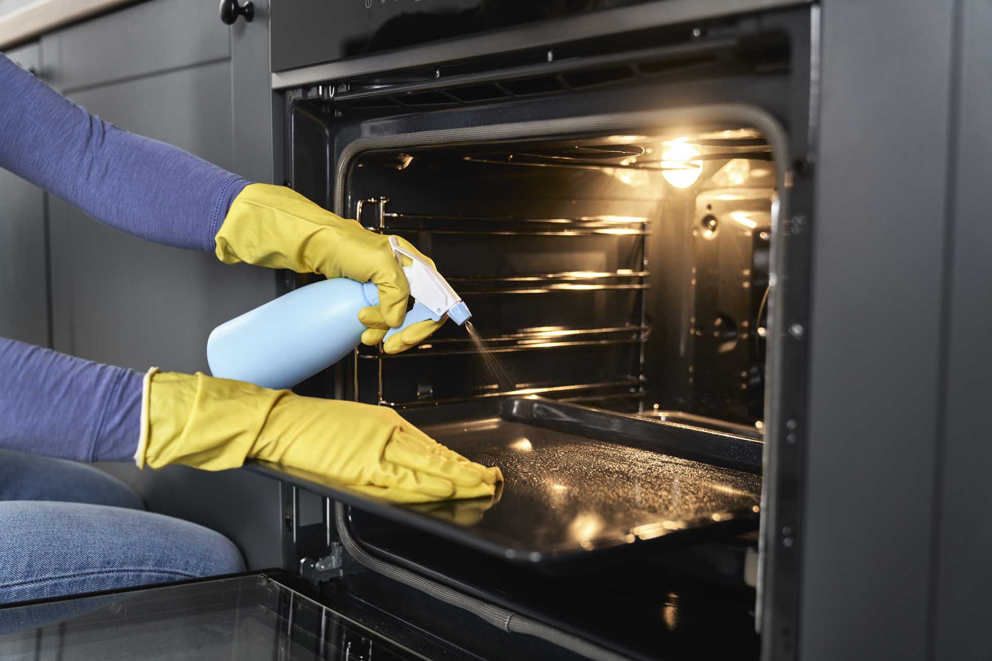 Close up of caucasian woman cleaning oven at home