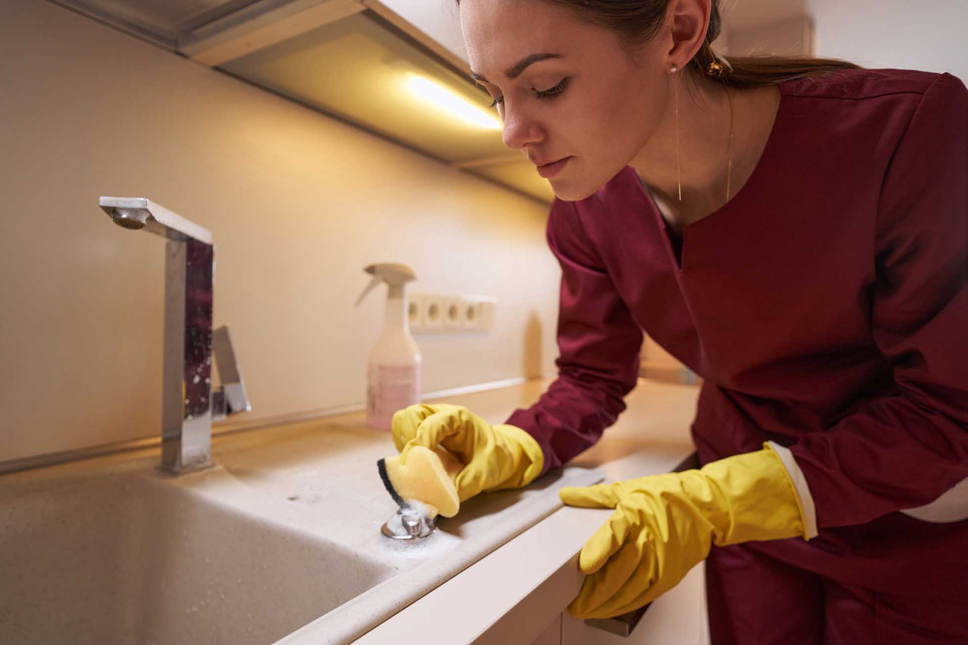 Concentrated serious professional janitor cleaning kitchen counter