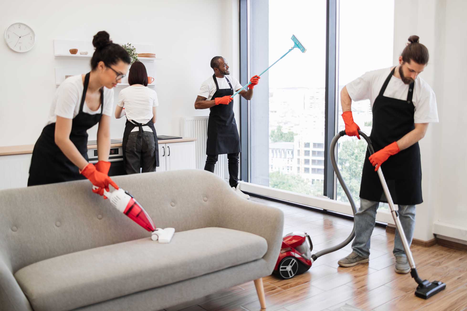 Team of service workers cleaning sofa, carpet, cuisine table and panoramic window.