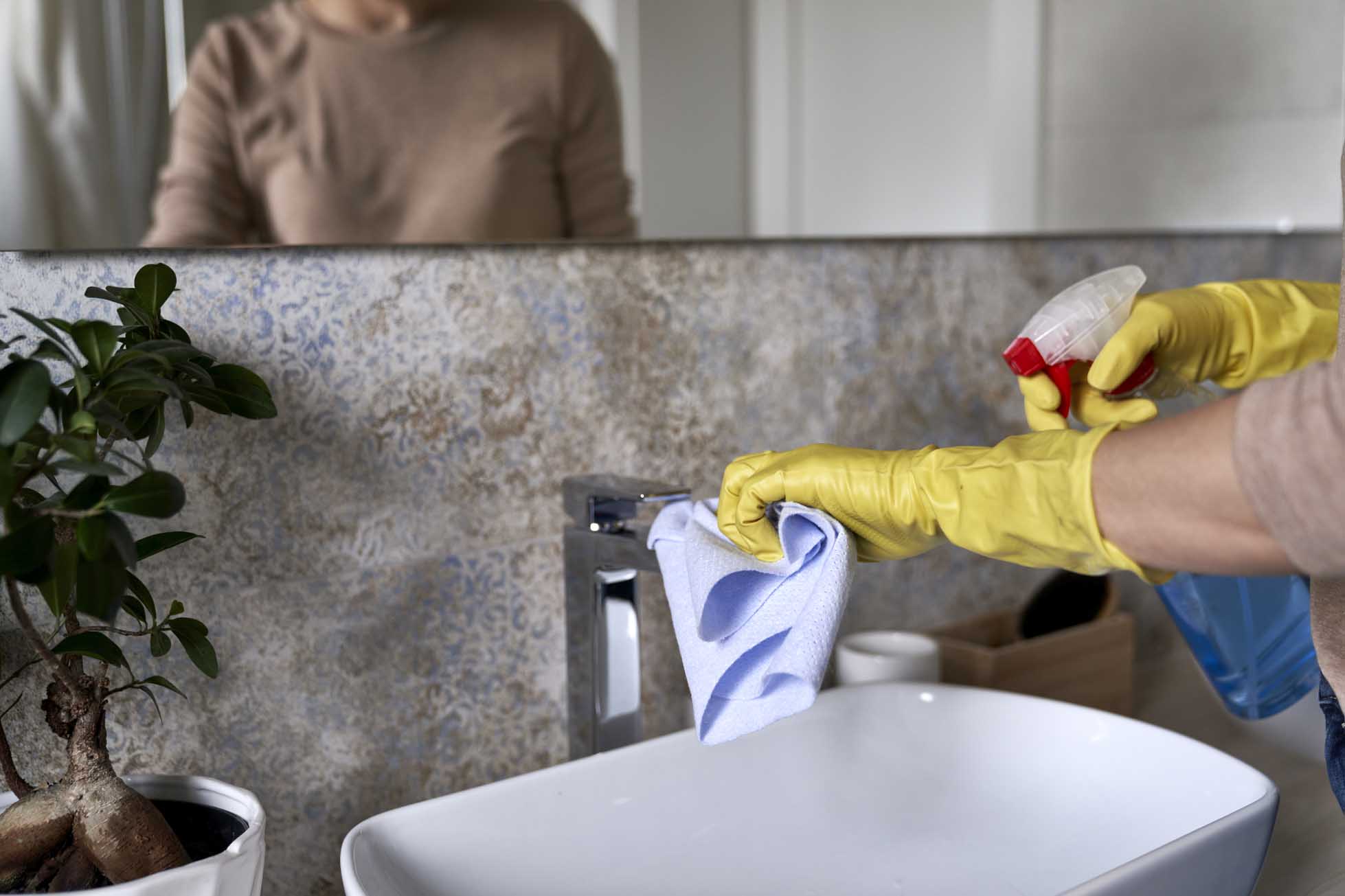 Unrecognizable woman cleaning bathroom tap